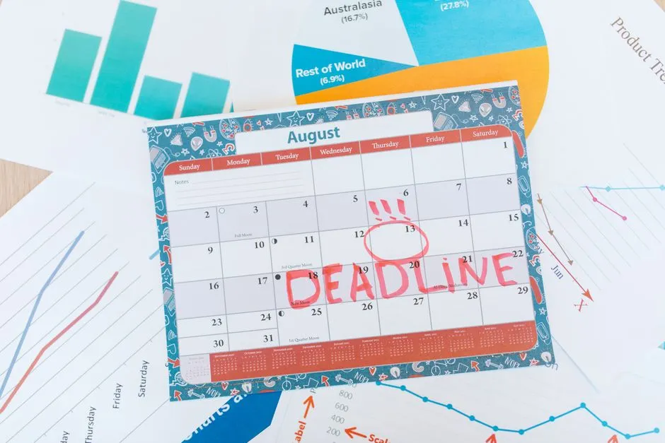 A monthly wall calendar lying on business charts with one date circled in red and the word deadline written across it