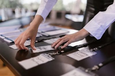 Close-up of hands arranging name tags on a conference table, preparing for a corporate event.