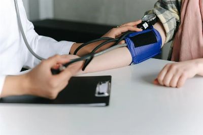 A healthcare worker uses a sphygmomanometer to check a patient's blood pressure in a medical office.