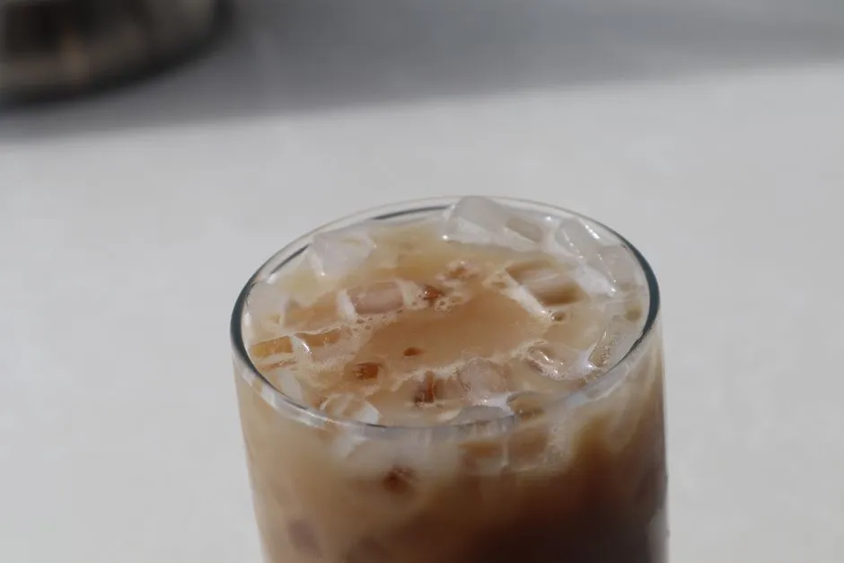 A glass of iced milk tea against a pale background.