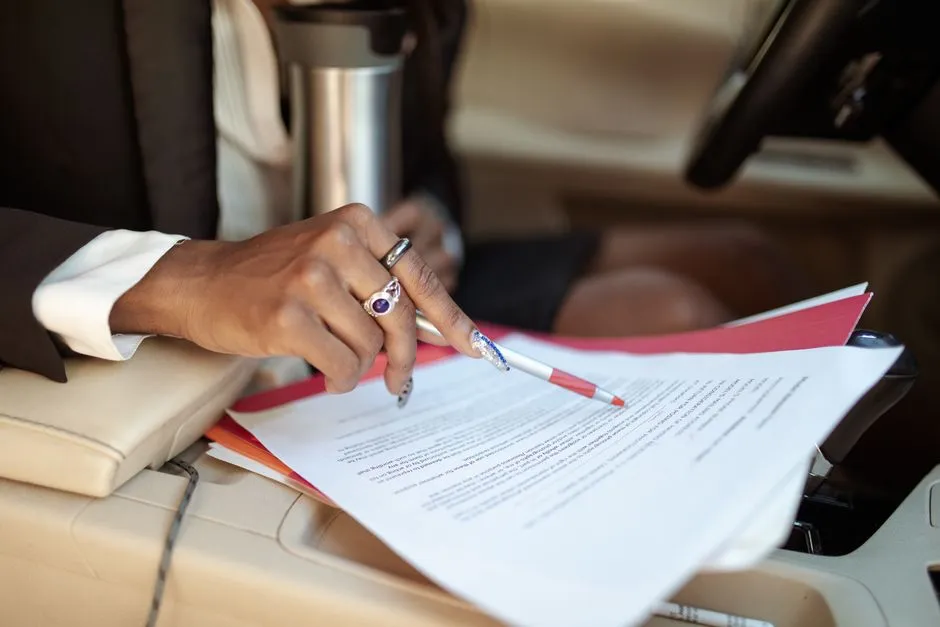 A professional reviewing documents in a car interior, focusing on hand and paperwork.