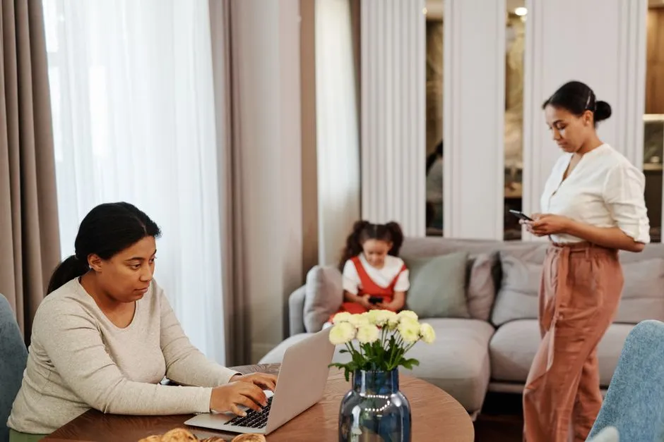 People sitting together in a living room, each using a separate device.