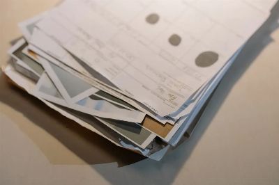 Close-up view of a stack of various papers and documents on a desk surface.