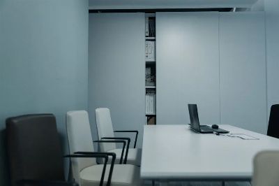 A sleek conference room with a white table and chairs, featuring a laptop on the table.