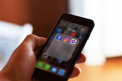 Close-up of hand holding smartphone showing social media apps like Facebook and Instagram.