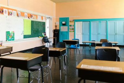 Bright and colorful empty classroom with desks, blackboard, and educational materials.