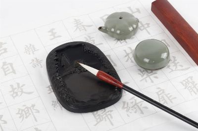 Flat lay of a traditional calligraphy set with ink stone, brush, and worksheet showcasing Chinese characters.