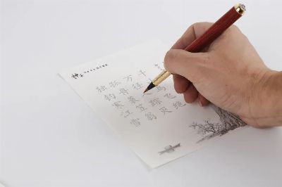 A person writing traditional Chinese calligraphy with a fountain pen on white paper.