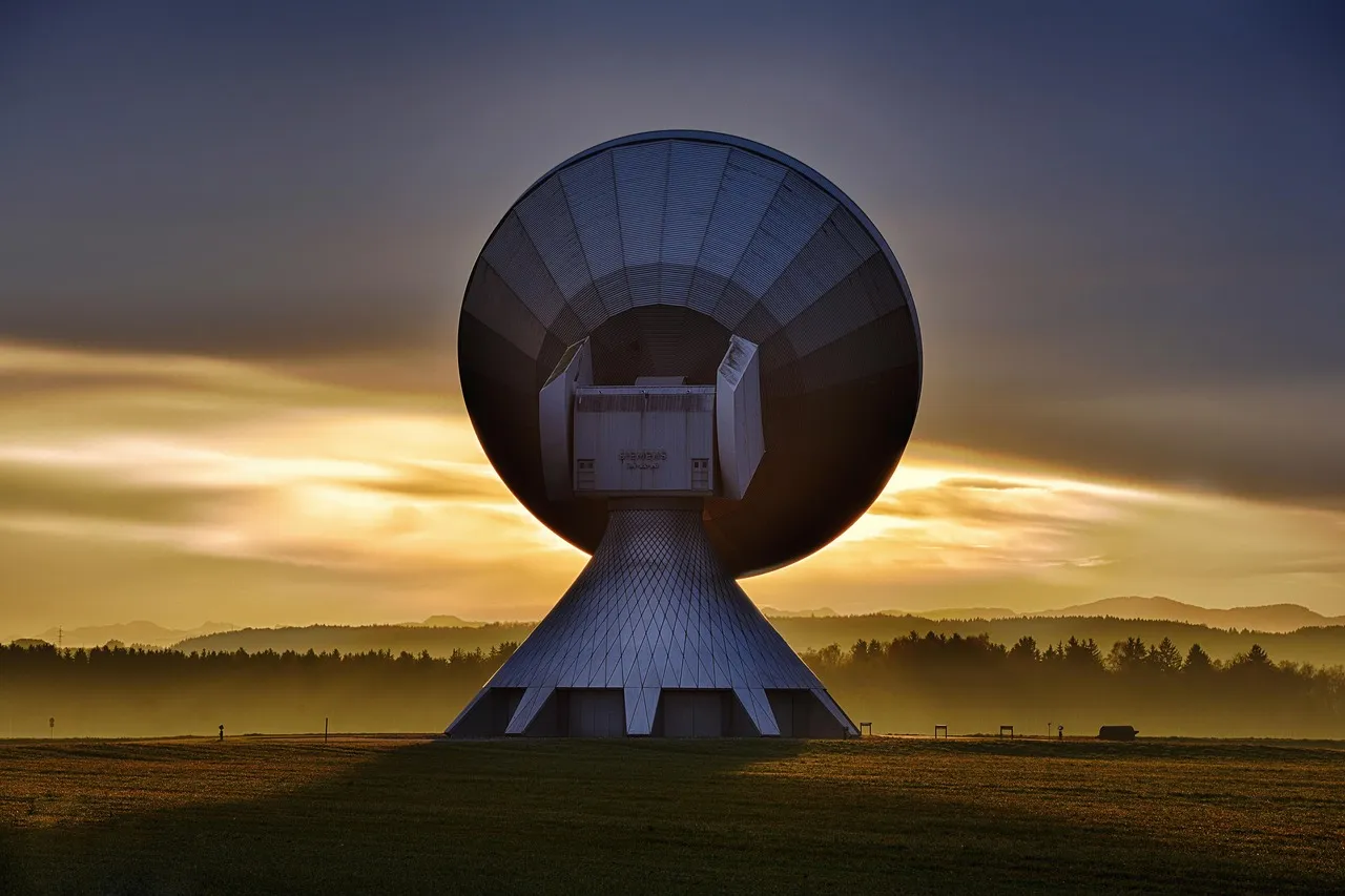 A large satellite ground-station dish at dusk