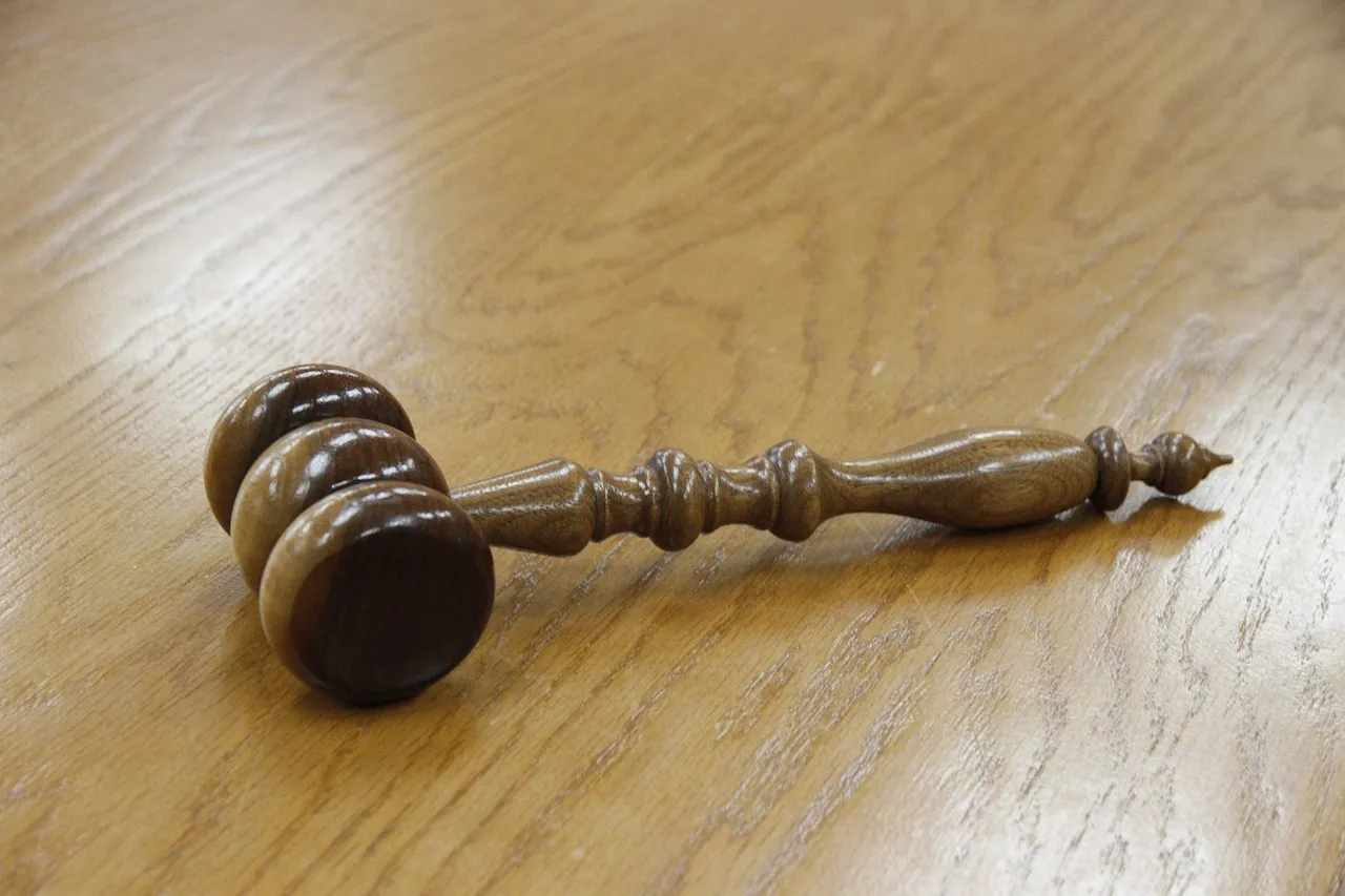 A wooden gavel lying on a light wooden desk