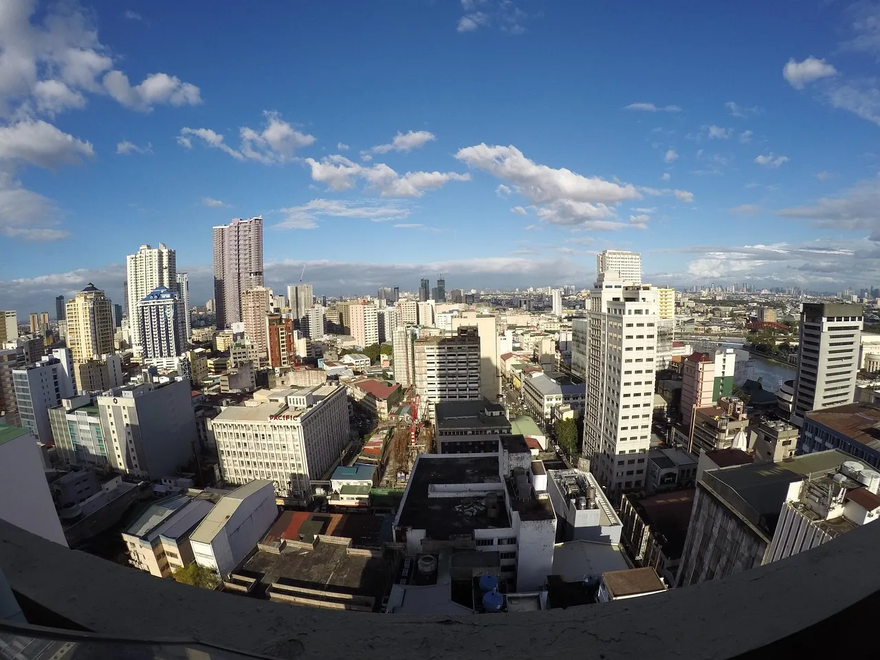 A daytime view over Manila with high-rise towers above dense low-rise blocks
