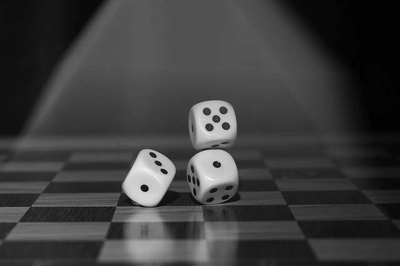 Three white dice resting on a chessboard under a shaft of light.