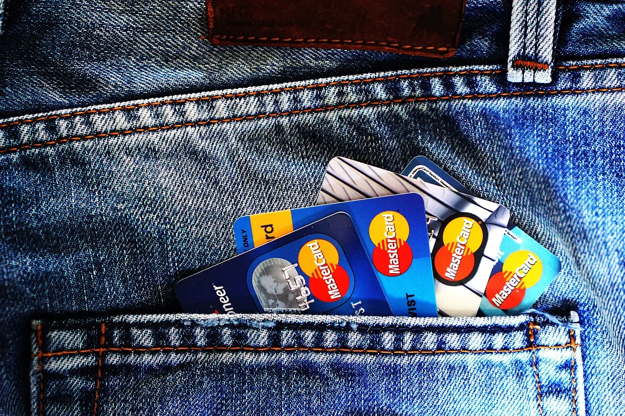 Several credit and debit cards tucked into the pocket of blue denim jeans.