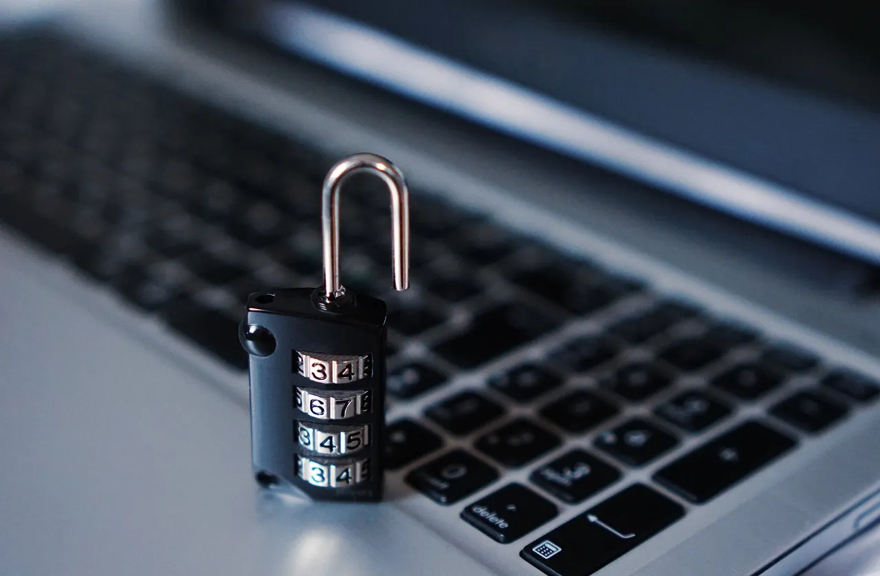 An open combination padlock resting on a laptop keyboard.