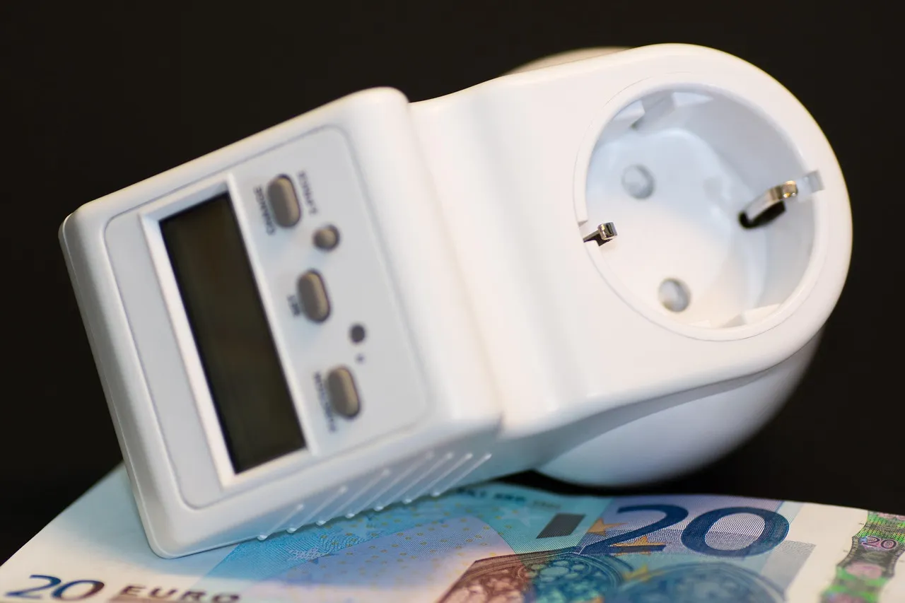 A plug-in electricity monitor with a digital display, resting on banknotes