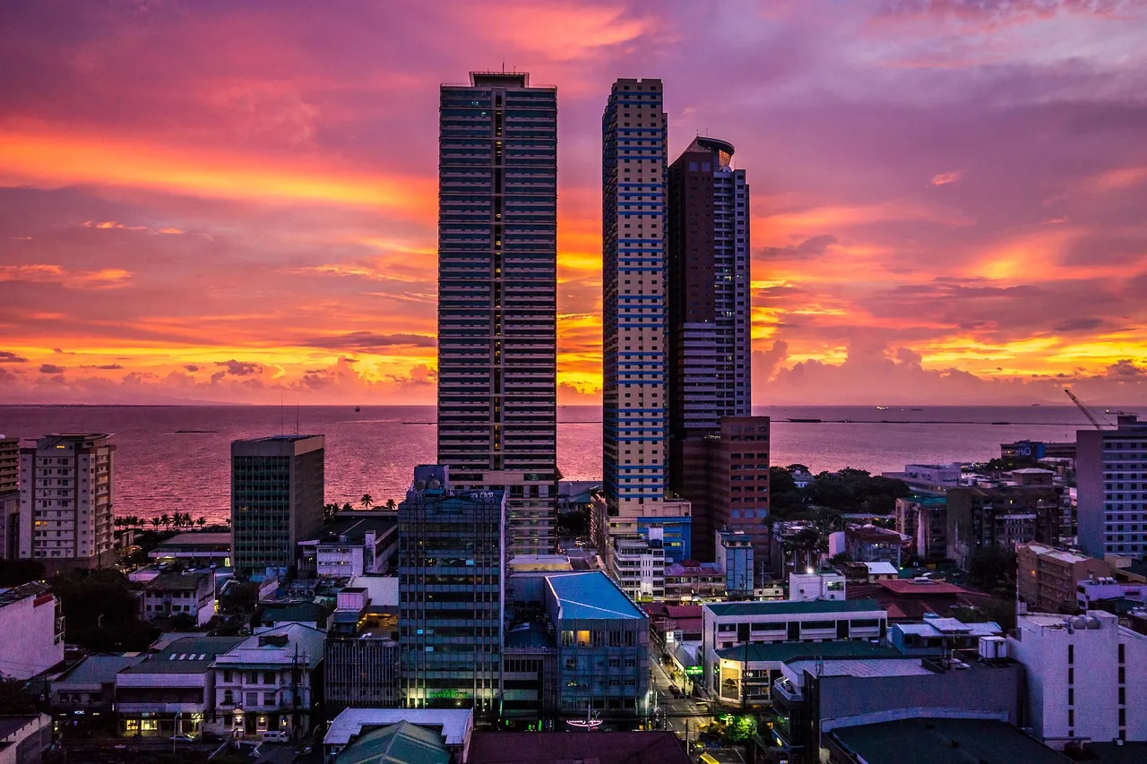 The Manila skyline at sunset, with high-rise towers standing above the surrounding city.