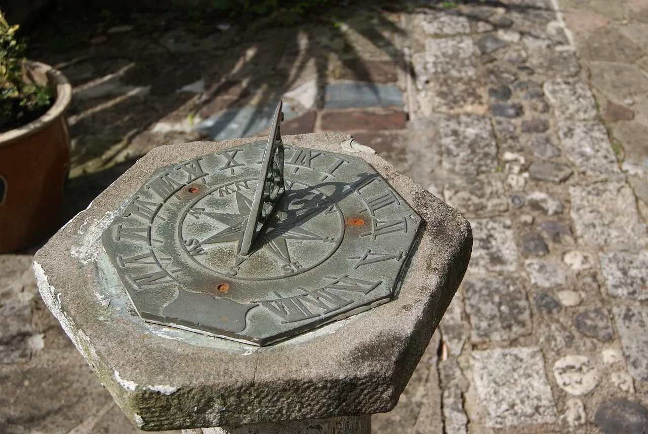 A weathered stone sundial, its gnomon casting a shadow across the engraved dial face.