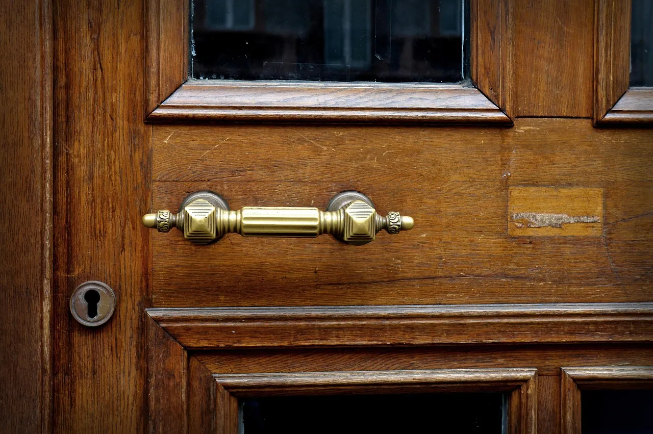 A heavy wooden door with a brass handle and an old keyhole, photographed close up
