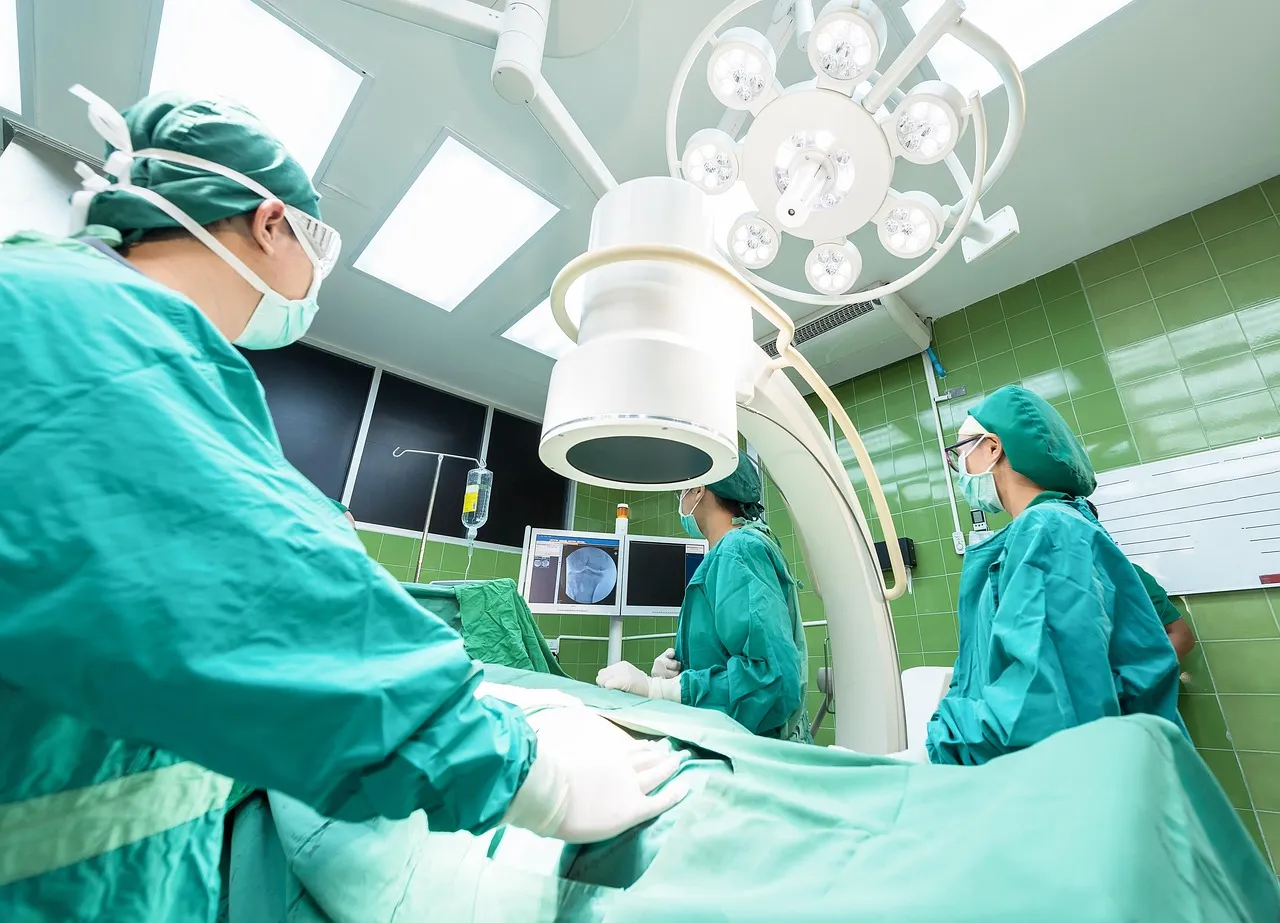 A surgical team working beneath theatre lights in a green-tiled operating room.
