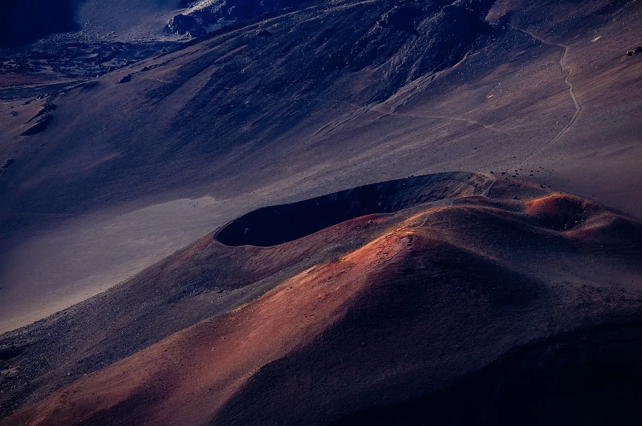 Cinder cones and a crater on a bare volcanic slope in low evening sun