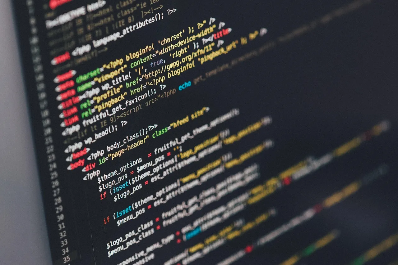 A close-up of syntax-highlighted PHP and HTML source code on a dark editor screen, shown at an angle with line numbers down the left