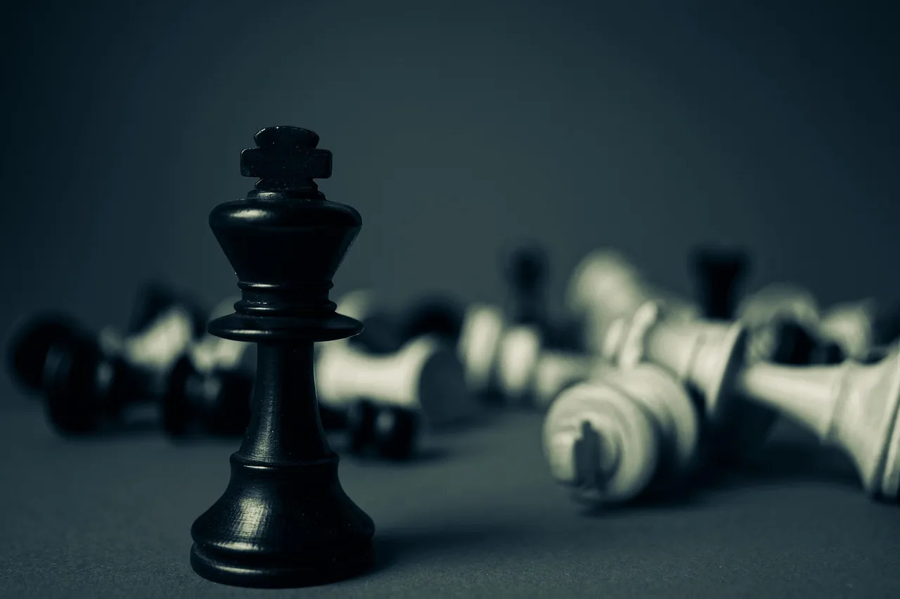 A black chess king standing upright among toppled white pieces