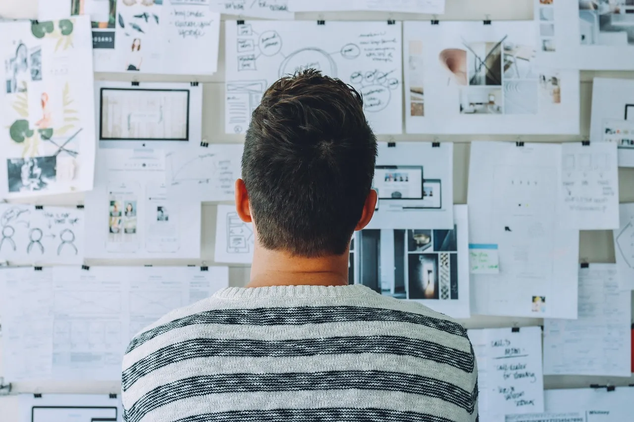 A researcher facing a wall of notes and sketches, the human work these agents were measured against