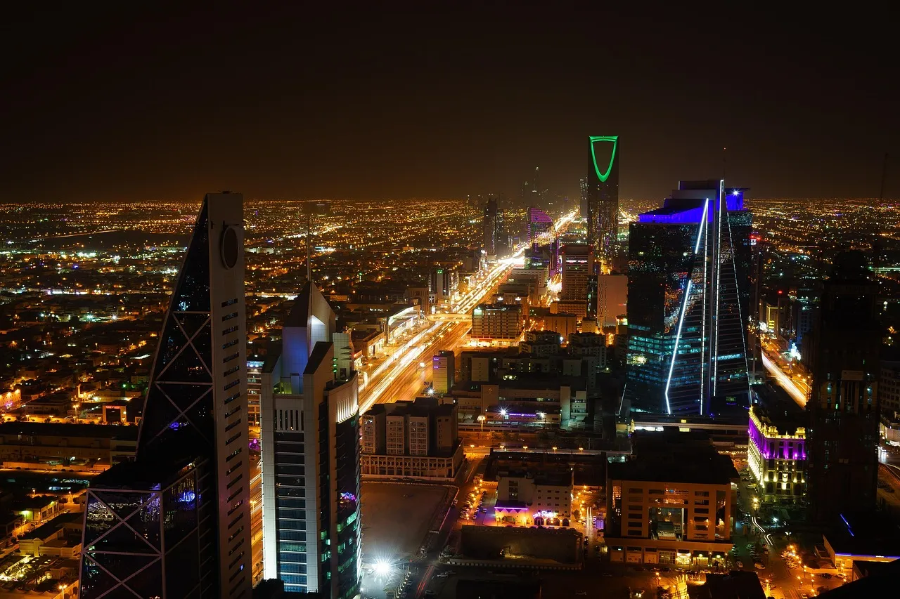 The Riyadh skyline at night, office towers lit above the city's traffic.