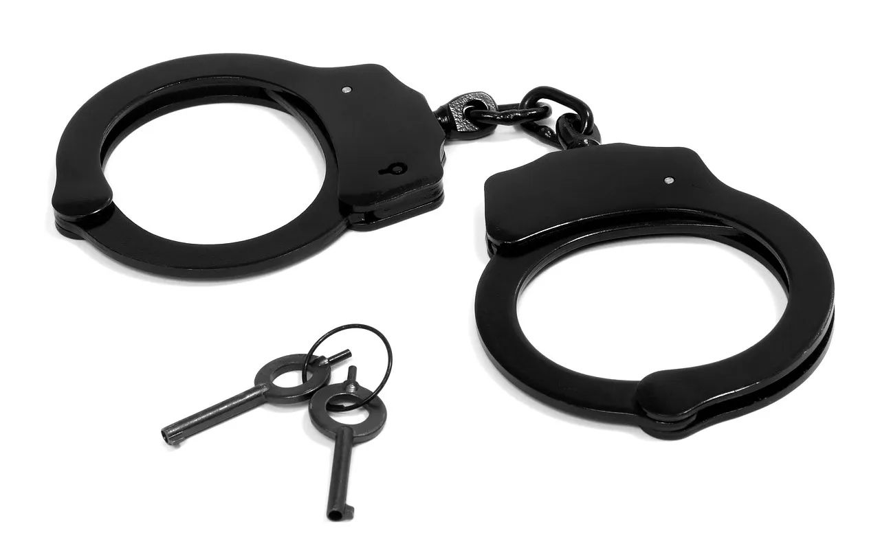 A pair of handcuffs with keys on a white background, representing the charges laid over the Shai-Hulud worm
