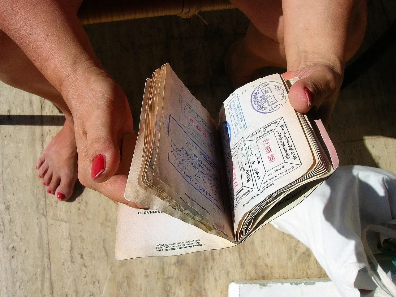 A person holding a well-used passport open at pages covered in visa stamps