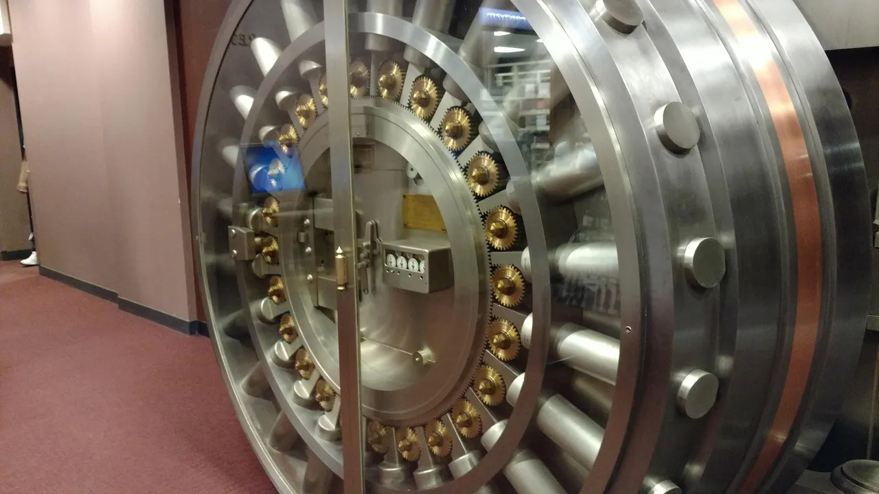 The open door of a bank vault, its steel locking bolts and brass mechanism exposed — illustrative of the incumbent settlement institutions now signing up to operate nodes on a new ledger.