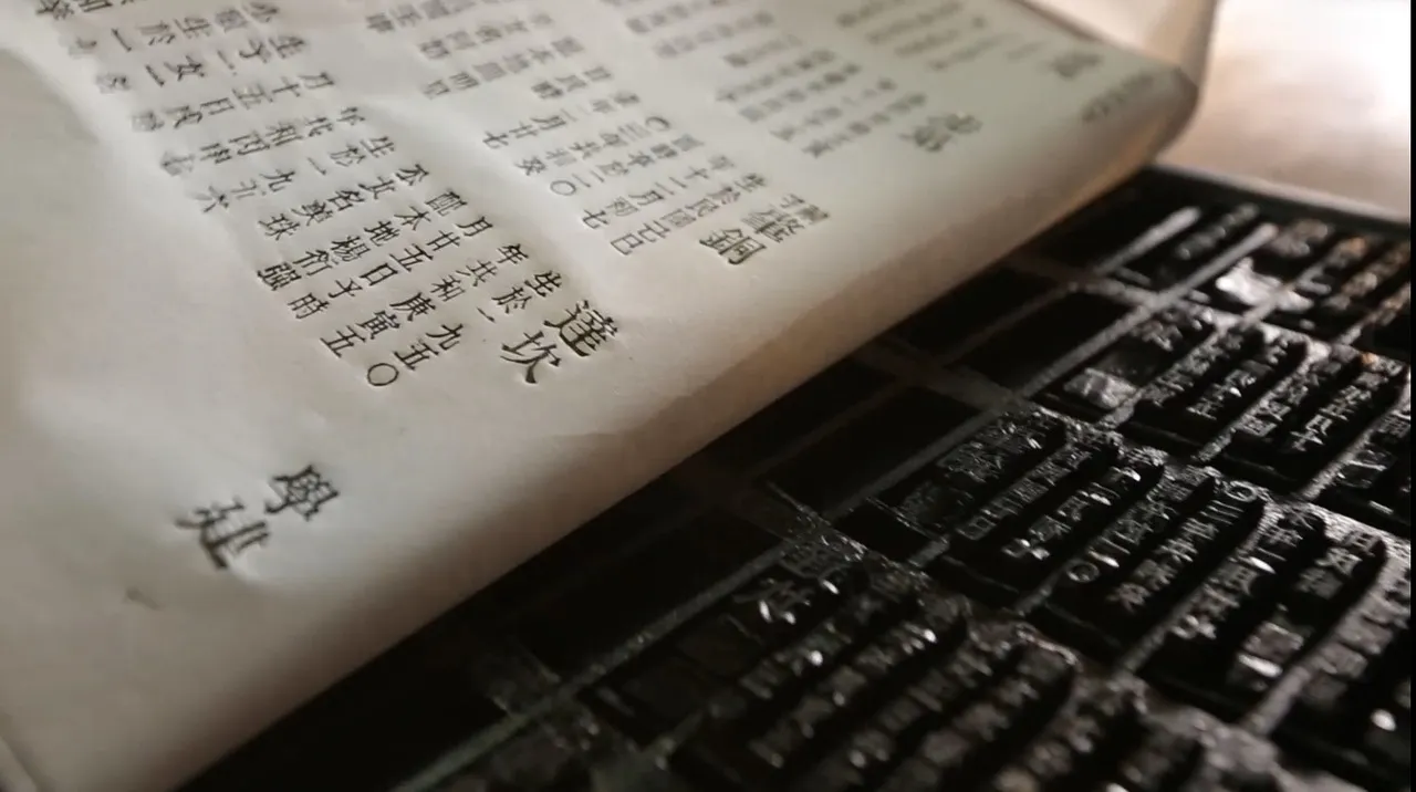 Trays of Chinese movable type beside a freshly printed page