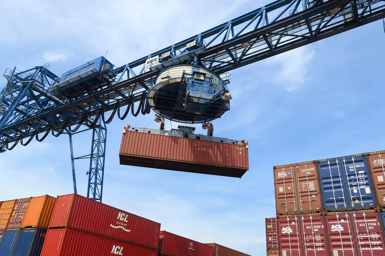 A crane lifting a shipping container at a port stacked with containers