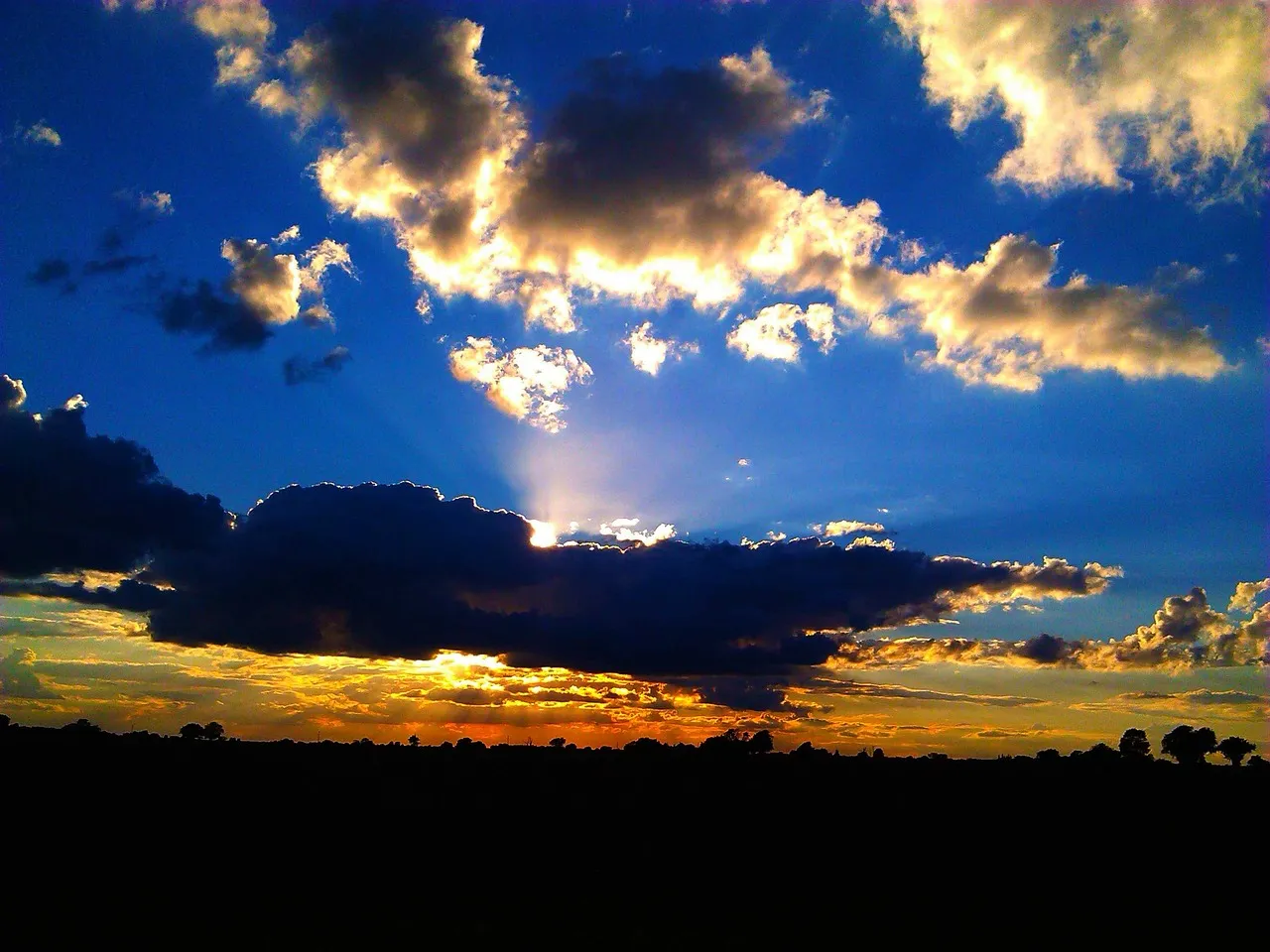 Sunlight breaking through clouds in a blue sky.