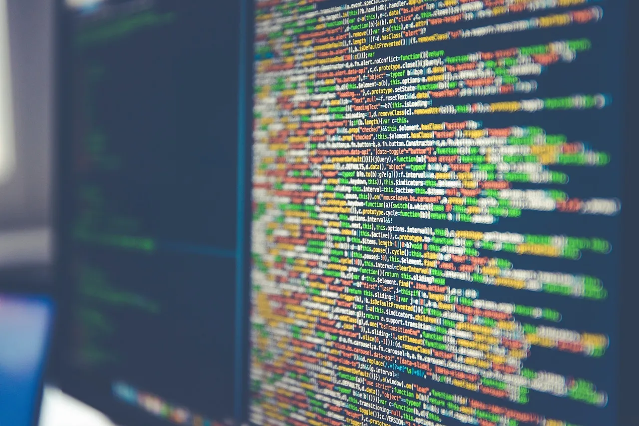 A monitor filled with colour-highlighted lines of source code, seen at an angle.