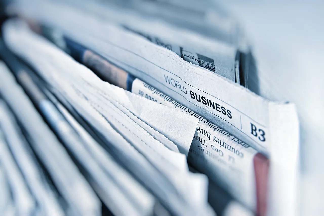 A row of folded business newspapers on a rack — illustrating the publisher whose pages now come in a second, machine-only edition.