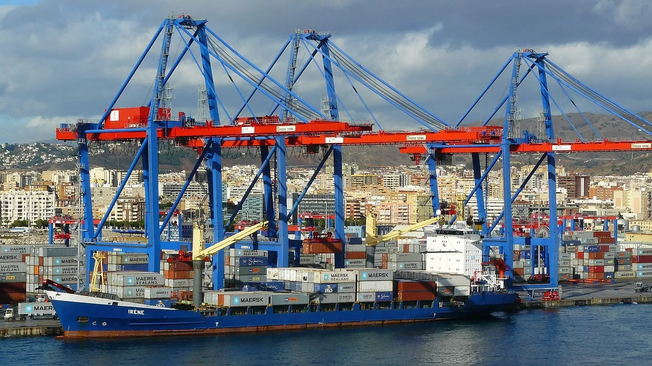 Gantry cranes loading stacked containers onto a cargo ship at a container terminal.