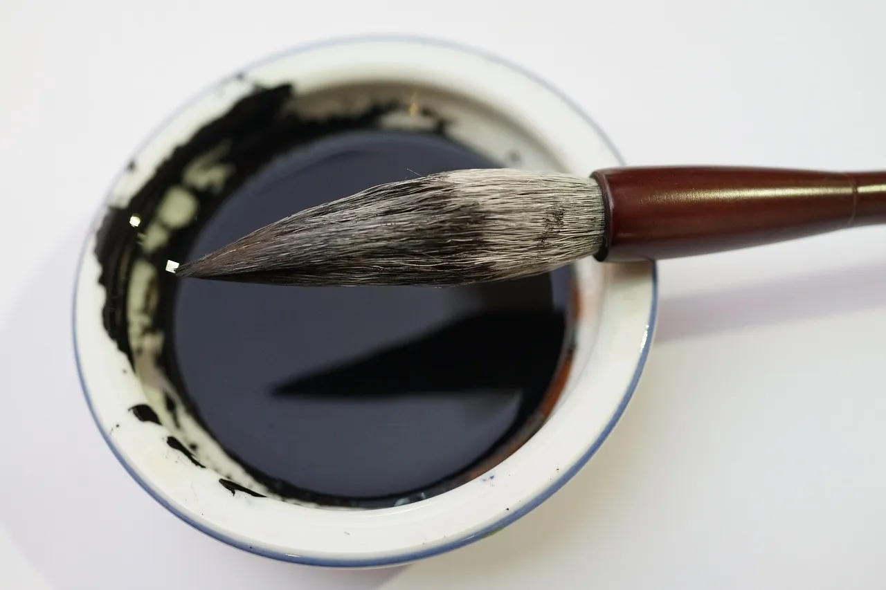 A Chinese calligraphy brush resting across a shallow dish of black ink.