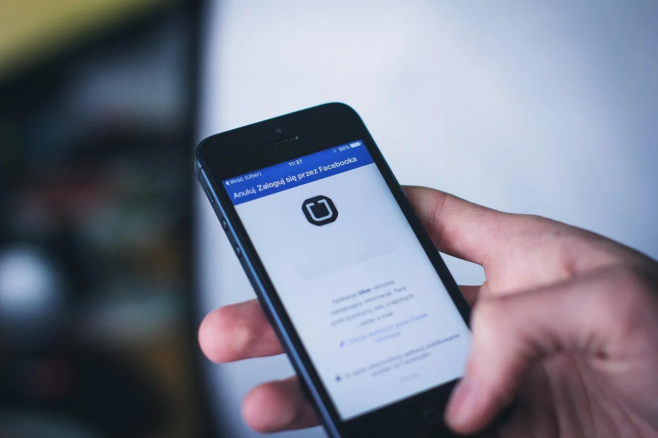 A hand holding a smartphone displaying a social media feed.