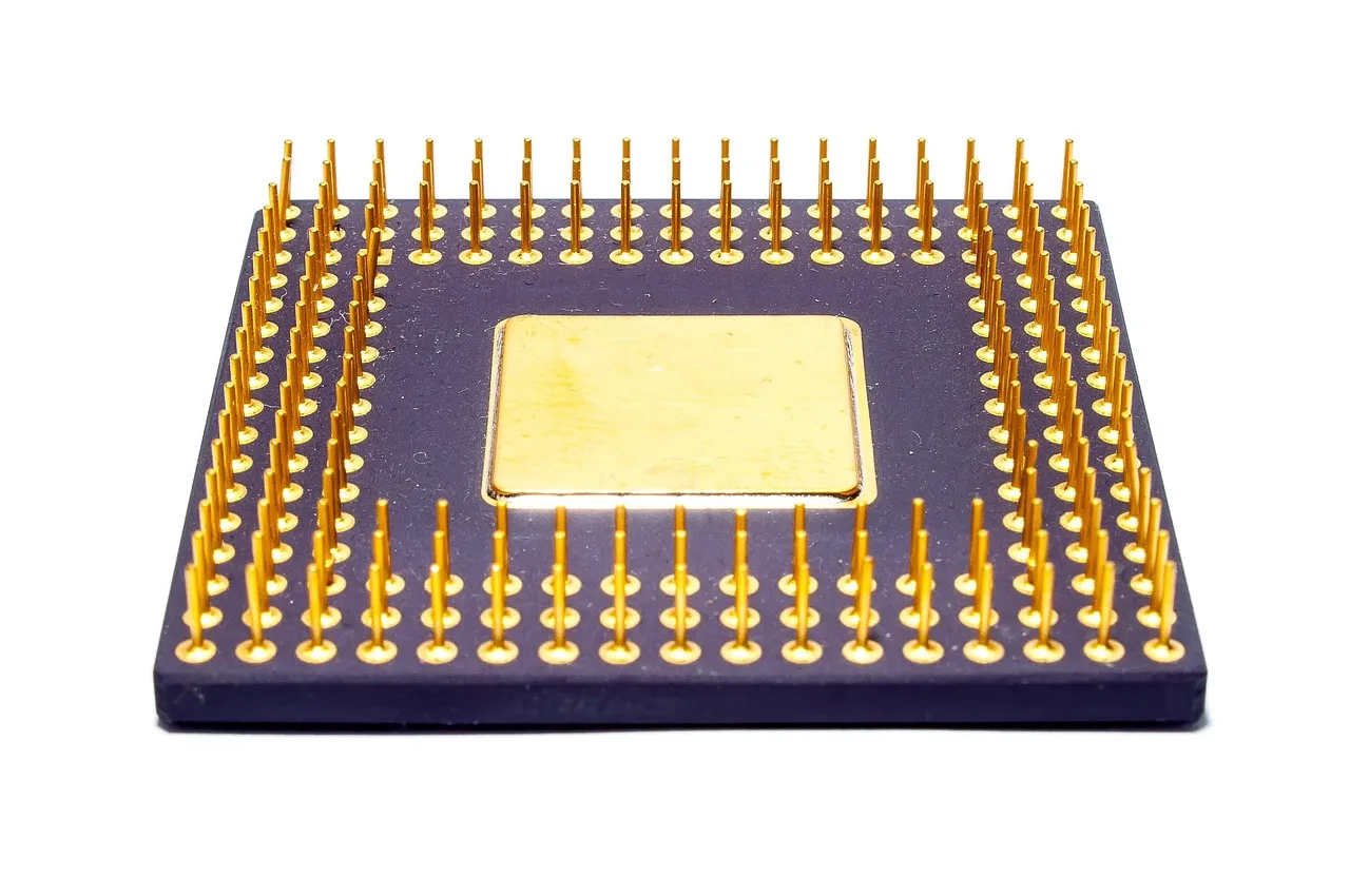 A ceramic processor package with a gold lid and rows of gold contact pins, on a white background.