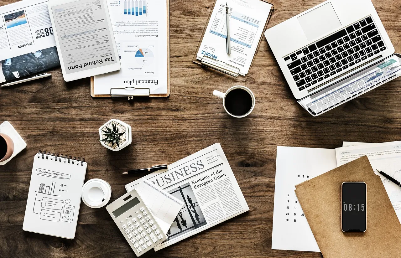 A desk laid out with printed reports, charts, a notebook and a laptop — illustrating the finance and operations managers this campaign selected for.