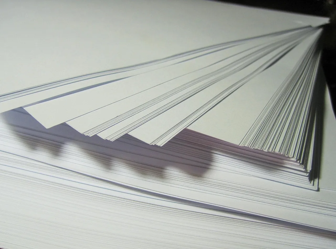A thick sheaf of loose papers fanned open on a pale surface
