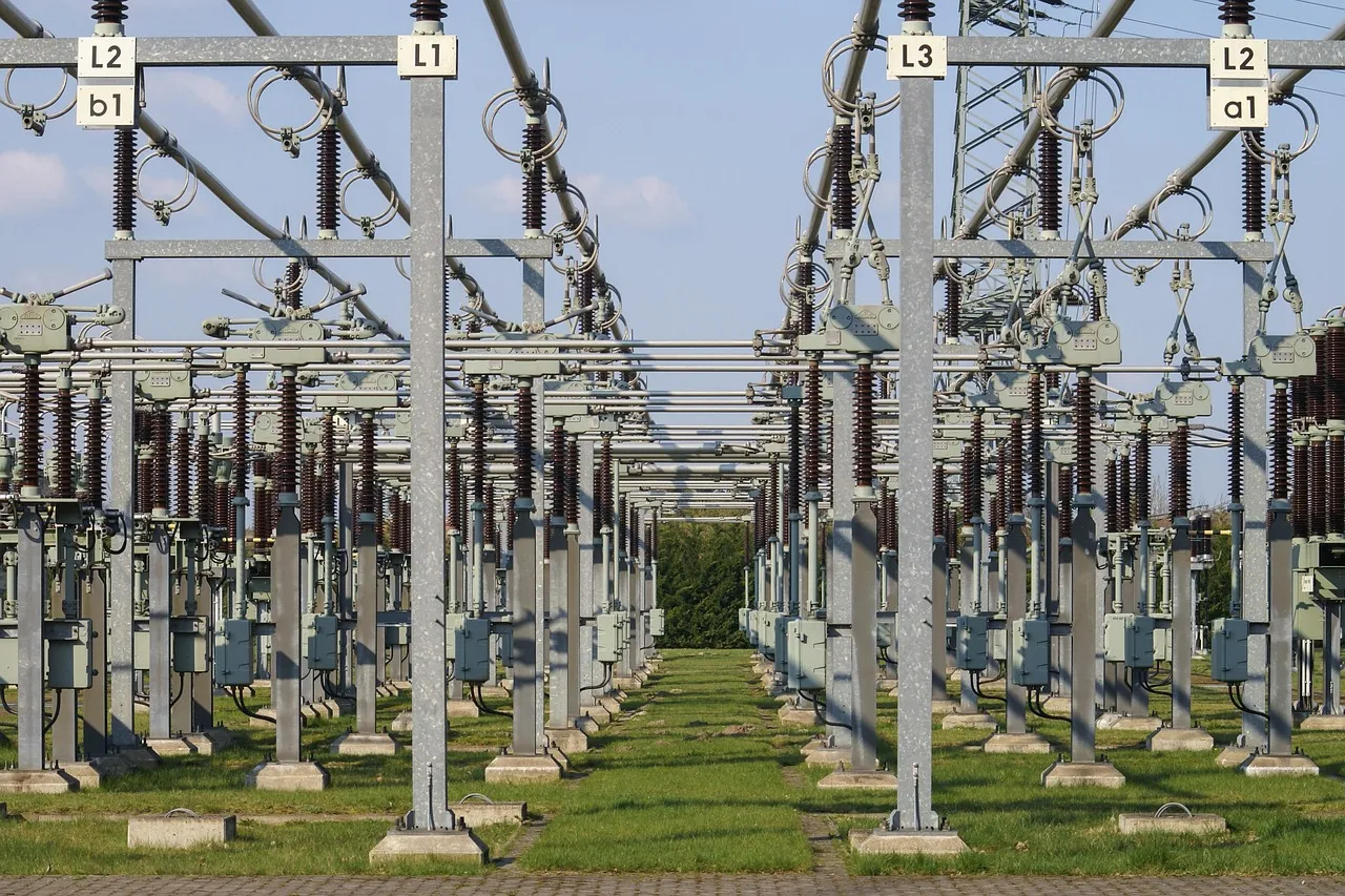 Rows of insulators and steel busbar frames in an outdoor high-voltage electrical substation.