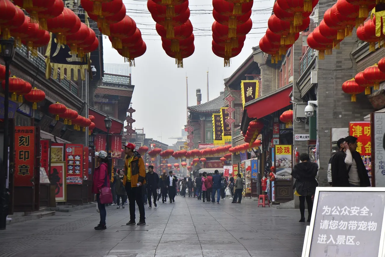 Red lanterns strung above a pedestrian street lined with Chinese shopfronts