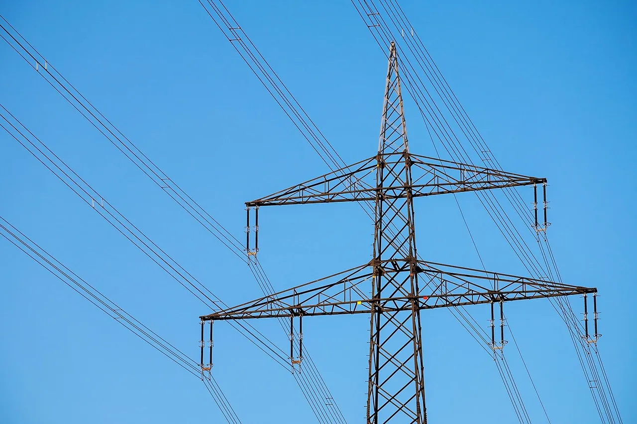 An electricity transmission pylon and power lines against a blue sky