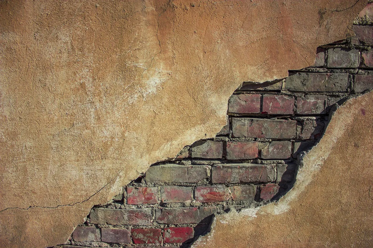 Old brickwork exposed where a layer of render has fallen away from a wall