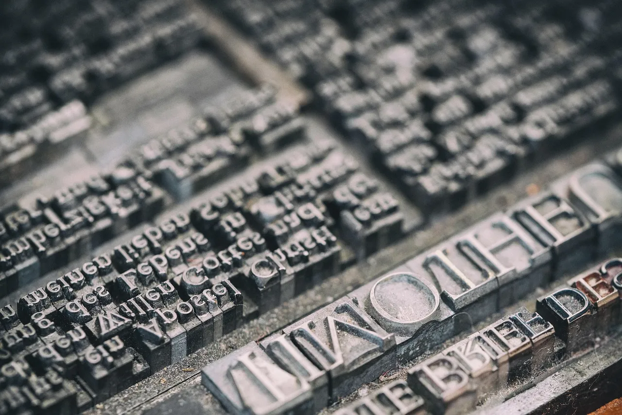 A tray of movable metal printing type, the letters in sharp focus in the foreground.