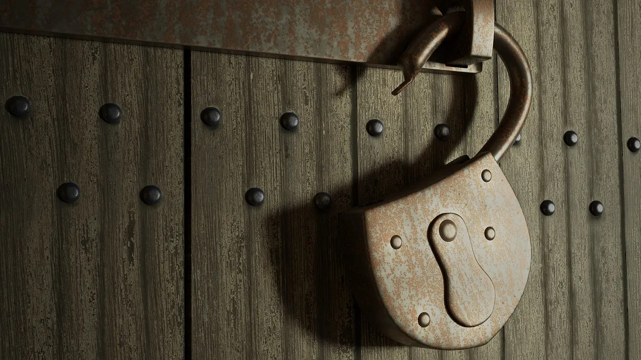 A large rusted iron padlock hanging from the hasp of a heavy studded wooden door. Its shackle is swung open and unlatched, so the lock is in place but fastening nothing.