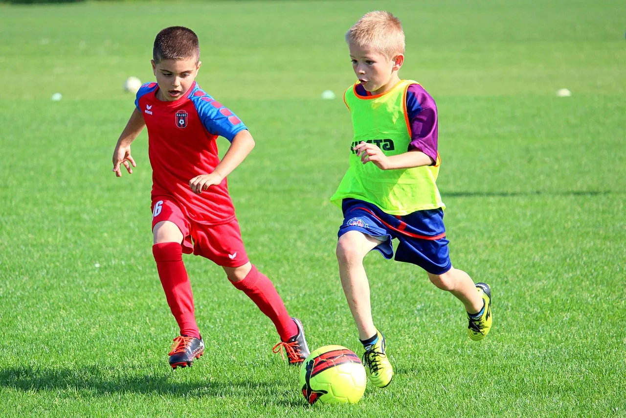 Children playing football on a grass pitch