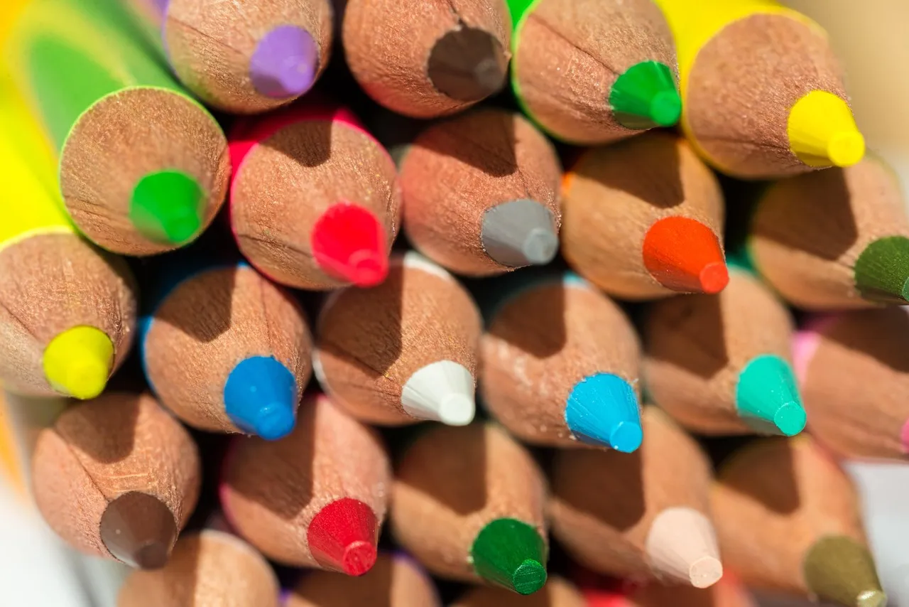 The sharpened tips of many coloured pencils packed tightly together, each one a distinct point of colour among its neighbours